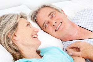 Zwei lachende Senioren kuscheln im Bett im Schlafzimmer